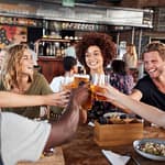 Group Of Young Friends Meeting For Drinks And Food Making A Toast In Restaurant